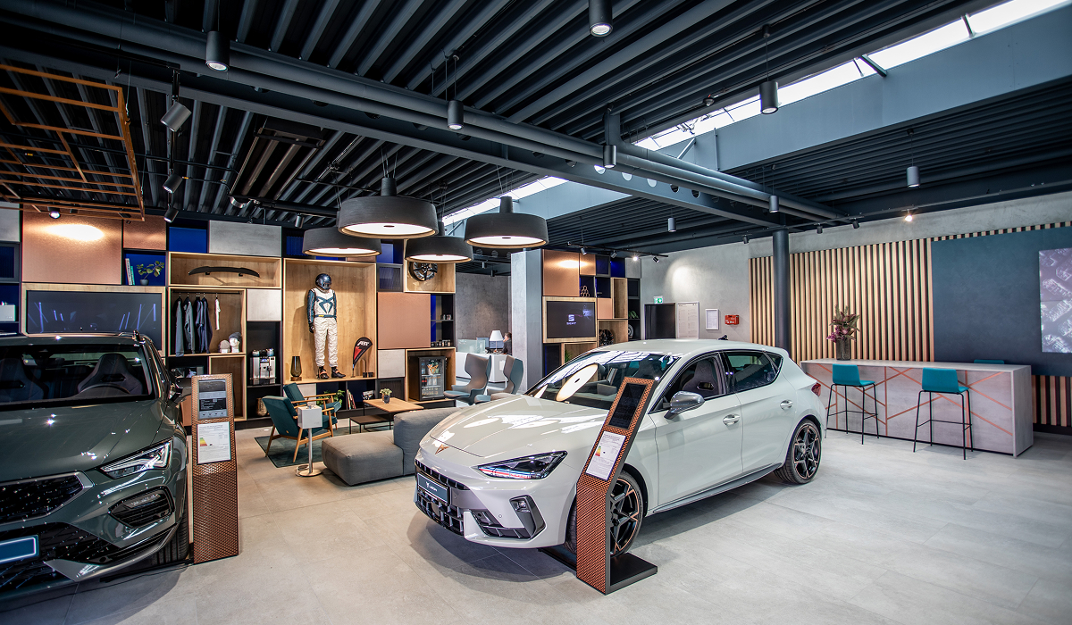 Lounge-Bereich der CUPRA Garage Hamburg mit großen Bildschirmen, CUPRA Branding und modernen Sitzmöbeln